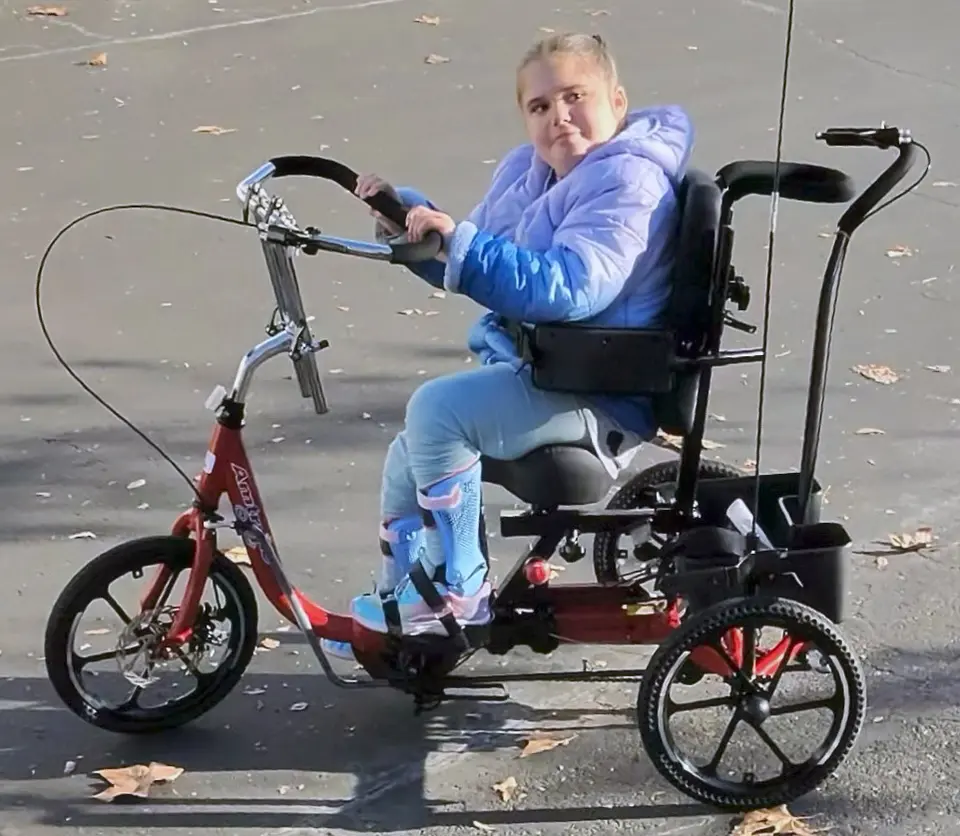 Rider seated on a red adaptive Tryke outdoors